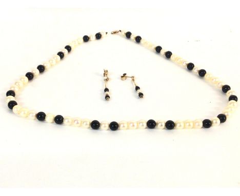 A Milkimoto black pearl necklace with conforming drop earrings. 9ct gold clasp.Postage B