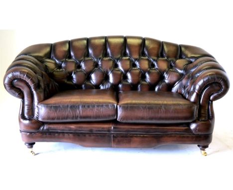 A Chesterfield Style Two-Seater Sofa, labelled Thomas Lloyd, upholstered in buttoned brown leather with rounded arms above tw