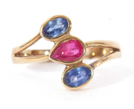 Sapphire and ruby three stone ring, a stylised design centring a pear shaped ruby between two oval sapphires, stamped 14k, si