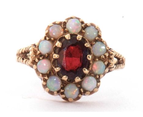 9ct gold garnet and opal cluster ring, the central garnet within a surround of 10 round cabochon opals raised between engrave