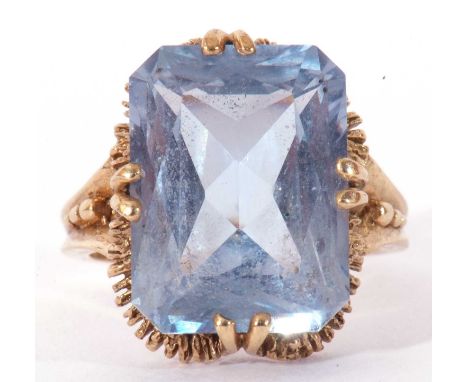 9ct gold light blue stone dress ring, the rectangular faceted stone cardinal set and raised in a textured basket mount, Londo