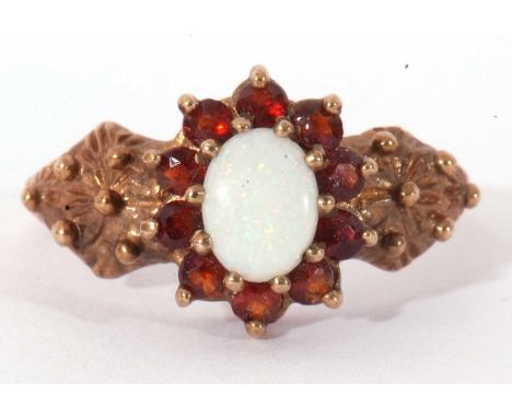 9ct gold opal and garnet cluster ring, the oval cabochon opal multi-claw set and raised above a small garent surround, having