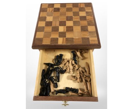 An inlaid storage chessboard, and a set of carved African chess pieces depicting figures and animals.