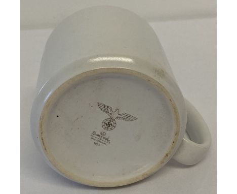 A WWII style German army white ceramic mug with printed markings to underside.  Approx. 9cm tall x 9cm diameter.