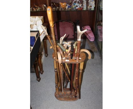 A STICK STAND CONTAINING A LARGE QUANTITY OF ASSORTED WALKING STICKS TO INCLUDE HORN HANDLED EXAMPLES, SHOOTING STICK ETC.