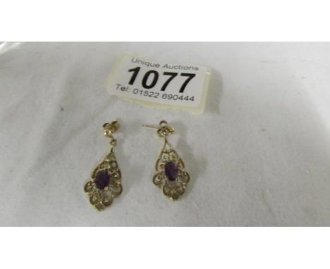 A pair of amethyst set ear pendants in gold.