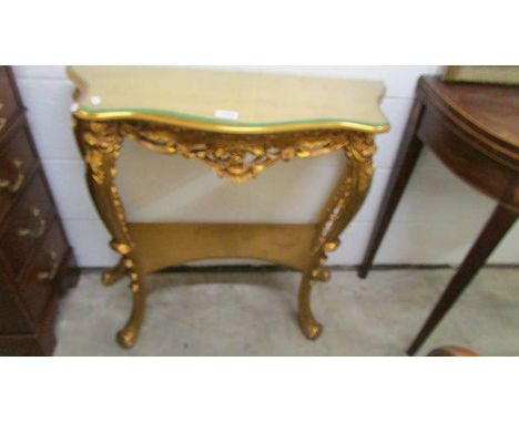 A gilded console table with glass top.