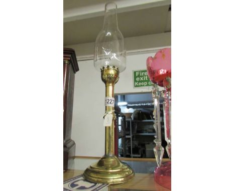 A brass candle lamp with glass chimney.