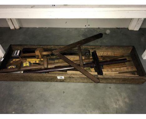 An old wooden tray of vintage tools including rulers,  spirit level etc.