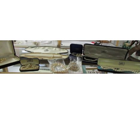 A small vintage vanity case containing various pearls with gold and silver clasps and assorted old jewellery cases.
