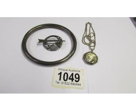 A silver locket on silver chain, a silver bangle and a silver brooch,