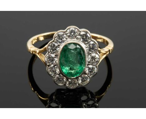 18CT GOLD EMERALD & DIAMOND CLUSTER RING, the central oval faceted emerald (8 x 6mms approx.) with a border of twelve round b