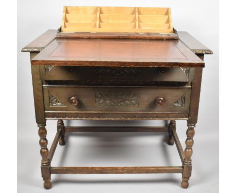 An Edwardian Oak Metamorphic Desk in the Form of a Two Drawer Chest which Opens to Reveal Tiered Stationery Rack, Red Leather