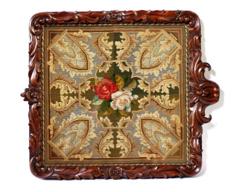 A Victorian needlepoint tapestry, urn with flowers, Gothic style surround framed in an ornately carved walnut frame, possibly