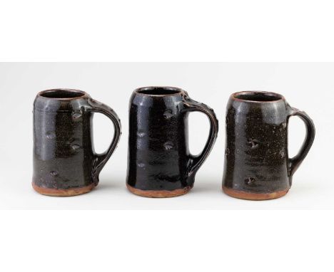 JIM MALONE (born 1946); a trio of large stoneware mugs covered in tenmoku breaking to kaki glaze with impressed decoration, i