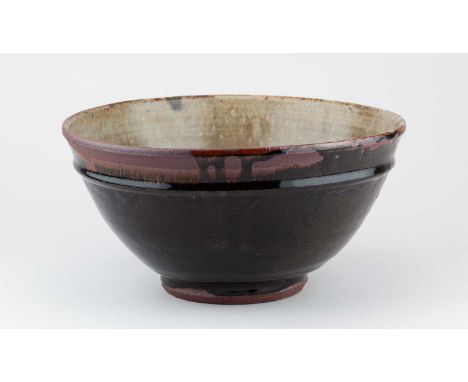 † JIM MALONE (born 1946); a large deep stoneware bowl covered in tenmoku breaking to kaki glaze with green ash interior pooli