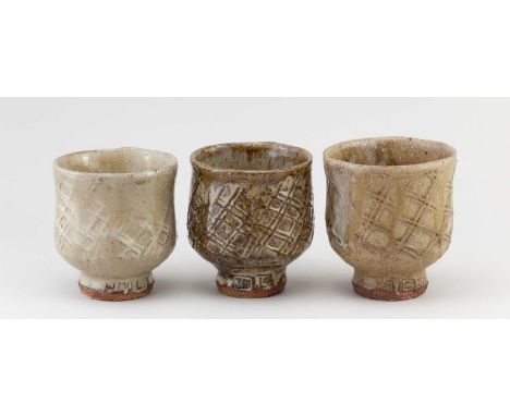 JIM MALONE (born 1946); a trio of stoneware yunomi partially covered in nuka glaze with paddled decoration, impressed JM and 