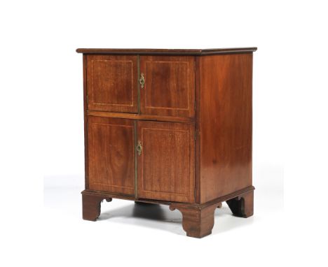 An Edwardian mahogany inlaid bedside cabinet. With two pairs of cupboard doors, inlaid with boxwood stringing, on bracket fee