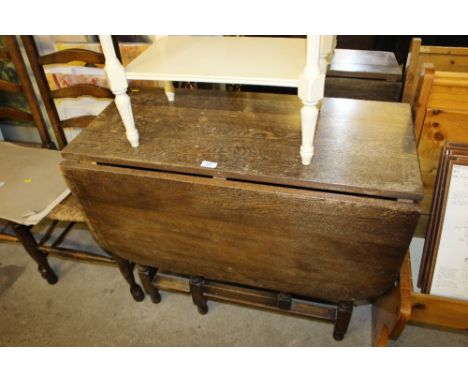 An oak gate leg dining table with two ladder back chairs