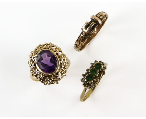 Three rings, one set with three round cut emeralds and Swiss cut diamonds, size K, another with oval cut amethyst with floral