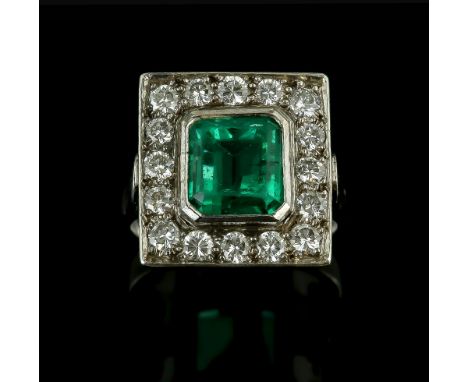 Vintage emerald and diamond cluster ring, central emerald cut 3.19 carats, set in a rectangular border of round brilliant cut