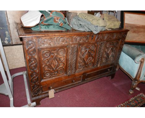 A mid 17th century oak coffer, with three deeply carved floral panels, having marquetry inlay, above two faux drawers, raised
