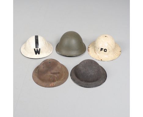 An interesting collection of six helmets, a Zuckerman pattern helmet painted cream with FG to the front, a white Brodie type 