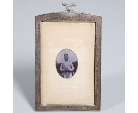 An oval portrait photograph of a young Edward, Prince of Wales, in a casual pose with jumper over his shoulders. Signed 'Edwa