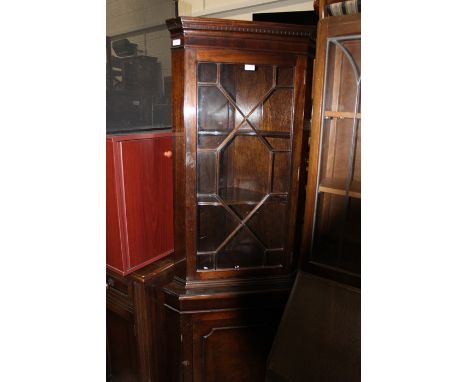 20th Century mahogany corner cupboard, the glazed door opening to reveal two shelves, above a paneled door, raised on bracket