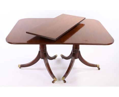 Regency style mahogany twin pillar dining table, with a rounded rectangular top above twin columns, together with one additio