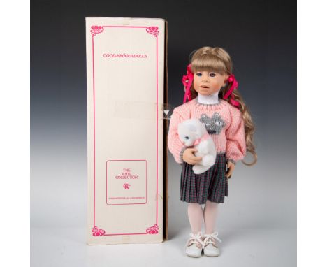 This limited edition (229 of 2000) vinyl doll with blonde hair, blue eyes dressed in pleated plaid skirt with pink cardigan h