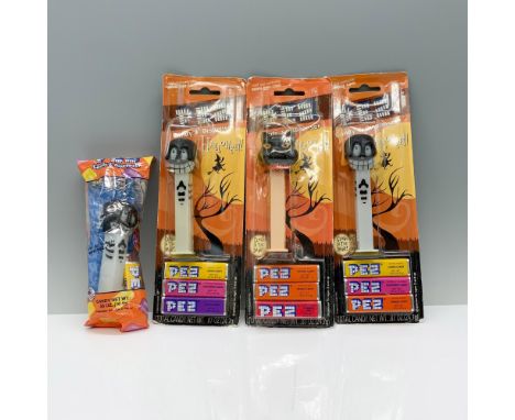 A set of 4 Pez Dispensers with three of the collection being a black skull with a toothy grin on top of a white handle and a 