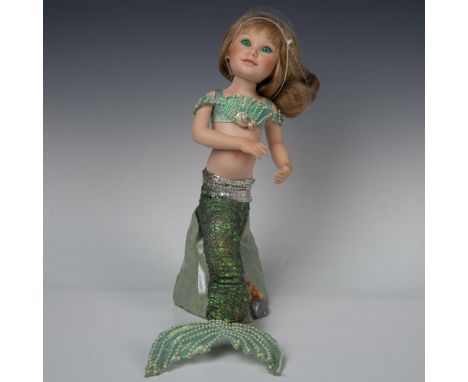 Serena is a mermaid in a cropped top, with a green tail. Pearlized beads on turquoise tail fin and top. Porcelain head, torso