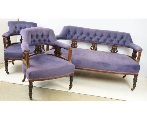 Pair of Victorian mahogany tub chairs with button backs and carved detail, on castors in purple upholstery with matching sofa