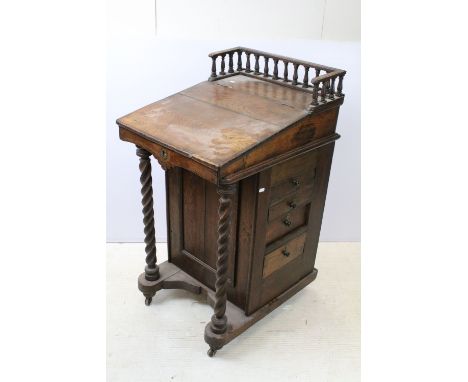 Late 19th century oak davenport, with galleried back above lifting writing slope, with four drawers to either side, with barl