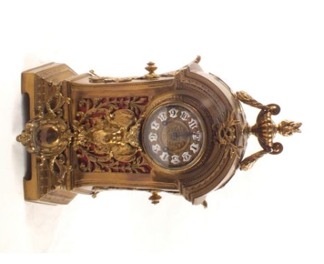 A brass cased mantel clock with winged cherub, leaf and urn decoration and enamel numerals