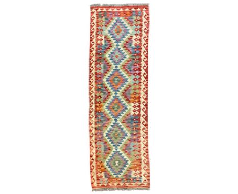 Chobi Kilim red ground and multi-coloured runner, decorated with overall geometric design, trailing lozenges within hooked bo