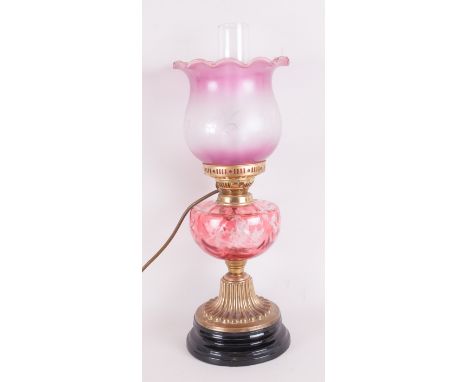 An Antique, now electric Oil Lamp with a cranberry glass shade and a flashed ruby font on a brass embossed base.