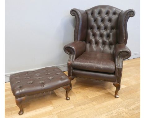 A leather button back armchair, scroll arms, dark brown, cabriole legs, 110cm tall (back), with a matching foot stool on cabr