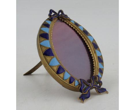 Christian Dior, an oval gilt metal and enamel picture frame, with bow detail, having an easel support, height 4.5ins