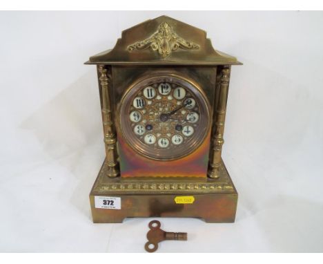 A brass cased French mantel clock, the case of architectural form flanked by cast brass decorative columns, white enamel dial