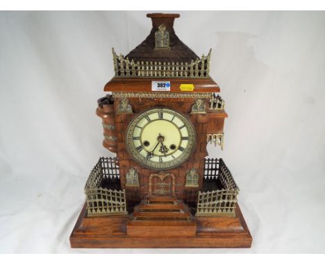 An unusual carved wooden mantel clock in the form of a castle with applied brass mount fences and canon, German made gong str