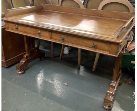 A light mahogany Edwardian writing desk, with three quarter gallery, moulded top, over two frieze drawers, on carved end supp