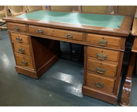 A 20th century oak pedestal desk, green tooled skiver, with the traditional arrangement of nine drawers, on ceramic casters, 