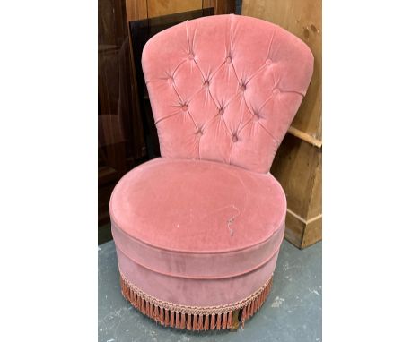A small pink button back bedroom chair 