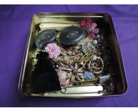 A tin containing a selection of costume jewellery including earrings, brooches, trinket boxes etc