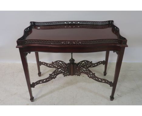 A CHIPPENDALE STYLE MAHOGANY CARVED SIDETABLE, with raised pierced gallery bowed ends on square cut tapering supports 70cms x