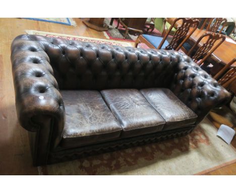 A BROWN LEATHER UPHOLSTERED CHESTERFIELD SOFA, the buttoned upholstered back and sides with loose cushions on castors 67cms x