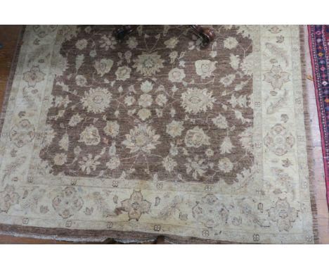 A WOOL RUG, the light brown and beige ground with central floral panel within a conforming border 234cms x 170cms