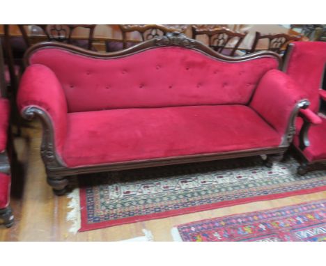 A 19TH CENTURY  MAHOGANY FRAMED SCROLLED END SOFA, the red velvet  buttoned upholstered back headed by a foliate cartouche wi